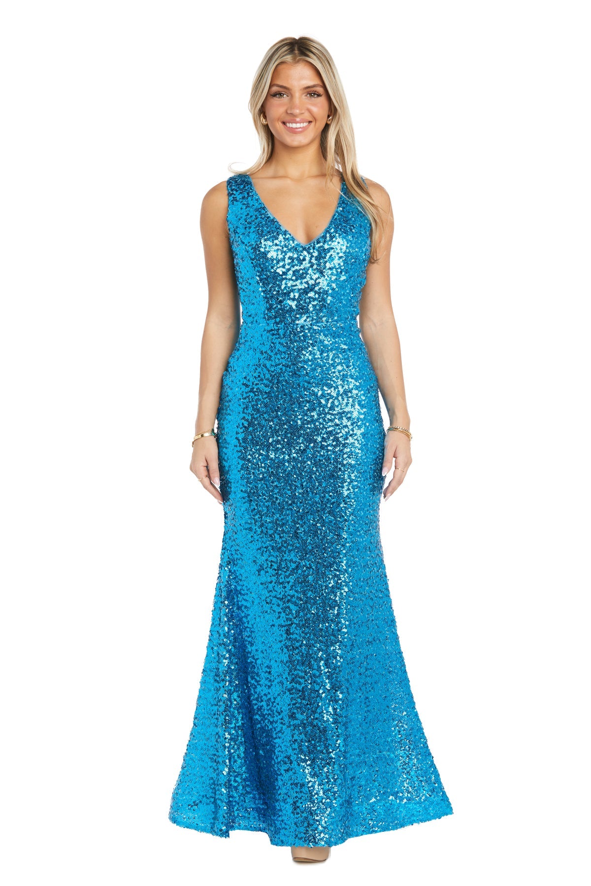 A woman stands smiling in the Long Sequin Prom Dress: Morgan 13313, a sleeveless, floor-length bright blue dress with a v-neckline and mermaid silhouette, against a white background.